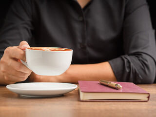 Businessman hand holding a cup of coffee sitting working at the office