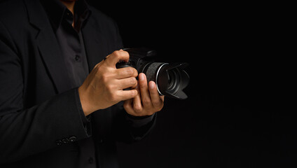 Close-up of hand holding the digital camera while standing on a black background