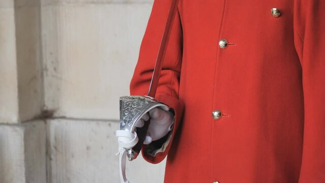 A view of a royal guard’s hand holding a sword.