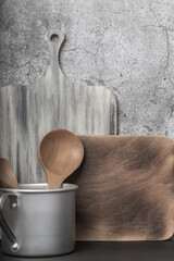 Kitchen retro background. Aluminum vintage mug, wooden cutting boards and spoon, kitchen utensils on the table. Household goods, tableware front view