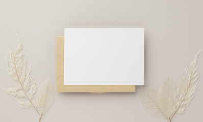 Blank greeting card invitation Mockup 5x7 on Brown envelope with dried flowers on beige background, flat lay, mockup