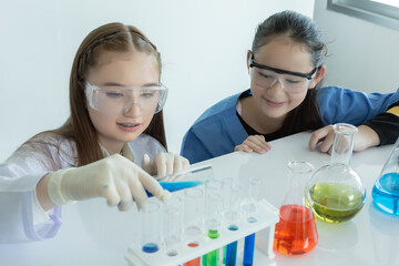 child girl science students study research liquid chemical experiments in white laboratory room. schoolgirl holding test tube with learning biotechnology. science education cocept.