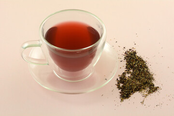 Rosehip hibiscus herbal hot tea in glass insulated teacup with saucer and herbal tea