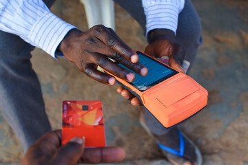 African hands doing business transaction with an ATM card and a point of sale terminal known as POS...
