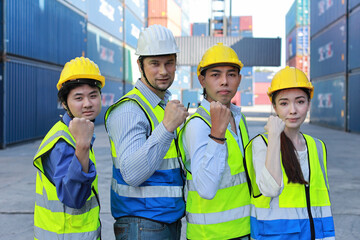 Group of multiethnic technician engineer and businessman in protective uniform with hardhat standing and raising hand celebrate successful together or completed deal commitment at container cargo site