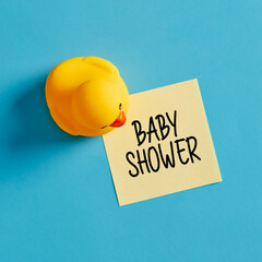 Baby shower party reminder message written on yellow sticky note with a rubber duck