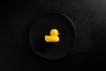 Rubber duck on a black plate. Eating duck meat or vegetarian and vegan food
