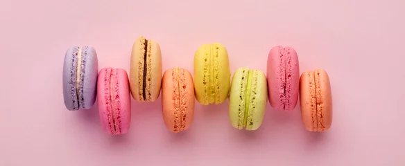 Raamstickers Colorful delicious French dessert macaron or macaroons in a row on pink background. © Cagkan