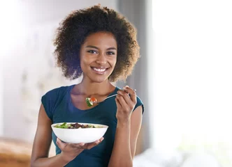 Fotobehang Getting her greens. Portrait of an attractive young woman eating a bowl of salad. © Mapodile M./peopleimages.com