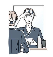 鏡の前で顔にムースをつける男性