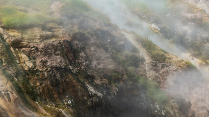 The hillside is shrouded in thick steam from an erupting geyser. Close-up. Poor visibility. Kamchatka. Valley of Geysers