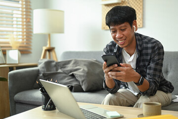 Smiling asian man chatting in social network or shopping online with smart phone.