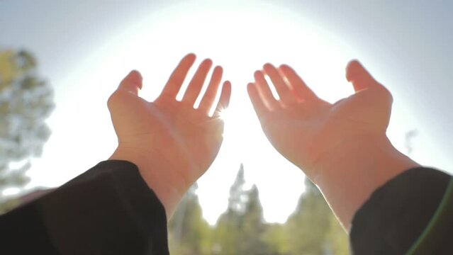 A person rises her hands towards the sky and makes a prayer