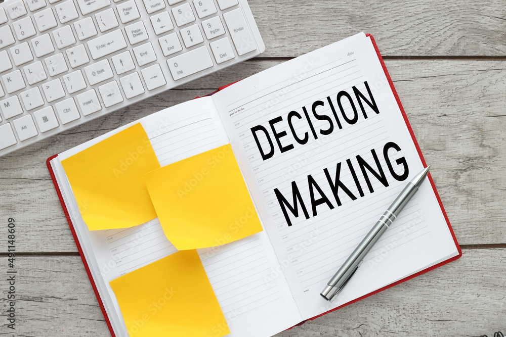 Poster open notepad on wooden background near yellow stickers and white keyboard. text in notepad. decision