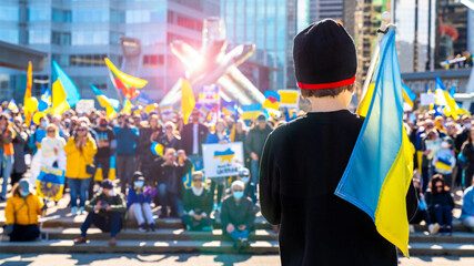 Young boy standing in front of a crowd at a protest against the Russian invasion in Ukraine. Child...