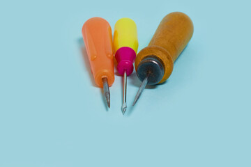 Sewing. Three multicolored awls on a blue background. 
