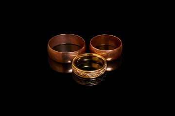 Three gold wedding rings on a black background 