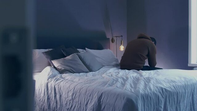 looking into bedroom where man sits in despair