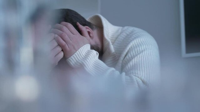 panning of man sitting at table with hands rubbing his head