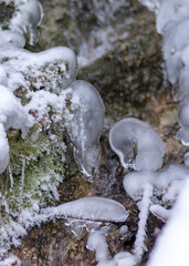 contrasts of frozen and running water, spring water flows over pieces of limestone, running water freezes to form various beautiful shapes