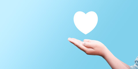 Male hand holding heart , like icon on blue background. Kindness, charity, pure love and compassion concept.Banner with copy space.