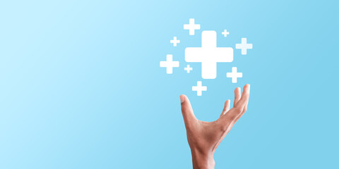 Male hand holding plus icon on blue background. Plus sign virtual means to offer positive thing...