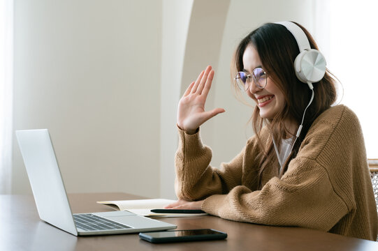 Young Asian Woman In Headphone Having Conversation Chatting While Using Laptop At House. Work At Home, Video Conference, Online Meeting Video Call, Virtual Meetings, Remote Learning And E-learning