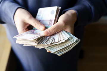 Russian rubles banknotes in hands during the war in Ukraine. Inflation, sanctions and the fall of...