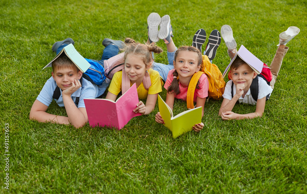 Wall mural Preteen students with books in park