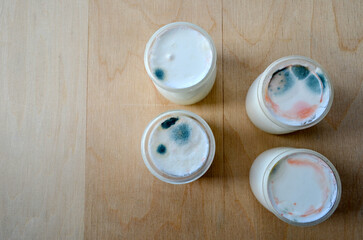 Fototapeta na wymiar moldy homemade yogurt in glass jars on a wooden table