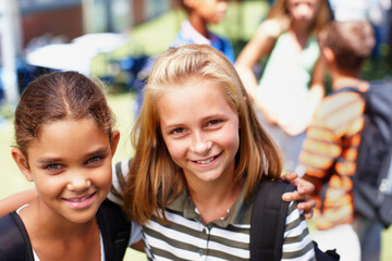 We love hanging out at school together. Two schoolgirl friends standing next to each other smiling up at the camera - copyspace.