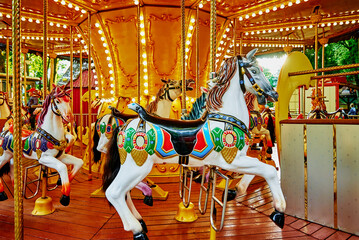 Carousel with colorful horses at amusement park, Merry go round with horse, Vintage ride attraction...