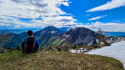 Male hiker having a break in spring on the summit of Frauenkogel in the Karawanks in Carinthia, Austria, Europe. Borders with Slovenia. Triglav National Park. Looking on Kahlkogel and Hahnkogel.