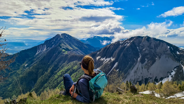 Female hiker having a break in spring on the summit of Frauenkogel in the Karawanks in Carinthia, Austria, Europe. Borders with Slovenia. Triglav National Park. Looking on Kahlkogel and Hahnkogel.