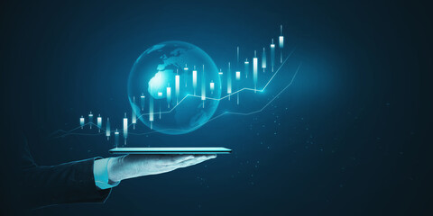 Close up of male hand holding tablet with glowing blue business chart hologram with globe on blurry...