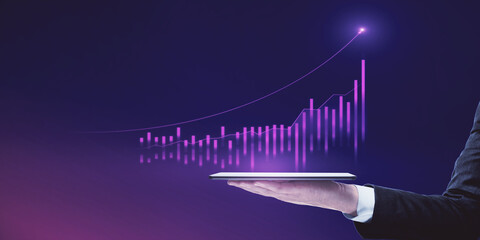 Close up of businessman hand holding tablet with abstract glowing growing global business chart on blurry purple background. Financial growth and trade concept.
