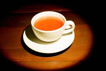 A cup of refreshing black tea, soft warm light for a morning meal, dark wood background.