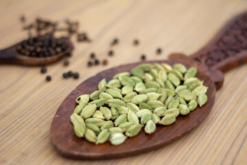 Heap of cardamom, clove on wooden background
