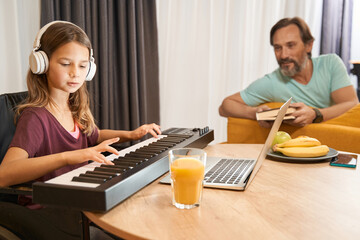 Disabled teenager learning to play synthesizer under supervision of father