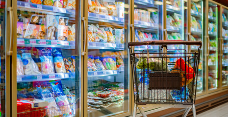 A shopping cart with grocery products in a supermarket