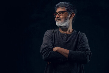 Fashionable hindu grandpa with crossed arms against dark background