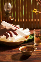 Rice paper roll decorated in wooden table with tamarind sauce and flower pot for food advertising 