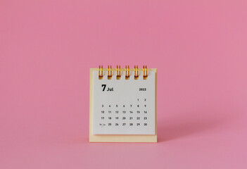Desktop calendar for July 2022 for planning on a pink background.
