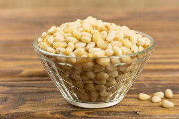 A bowl with pine nuts on a wooden background, delicious, natural. Soft focus.