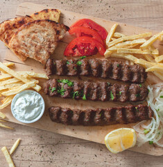 Shish kebab, doner souvlaki, roasted meat, pita bread, tzatziki and vegetable on wood, overhead