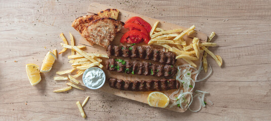 Shish kebab, doner souvlaki, roasted meat, pita bread, tzatziki and vegetable on wood, overhead