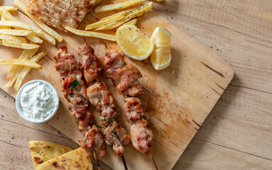 Souvlaki dish, Greek meat food. Grilled chicken skewers and pita bread on wooden table, overhead