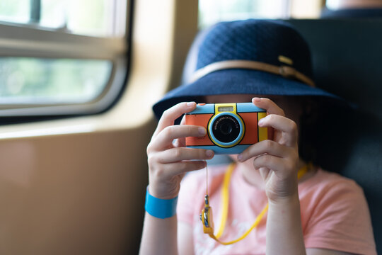 portrait of child with camera on a train taking photos