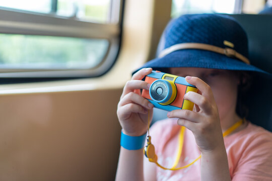 portrait of child with camera on a train taking photos
