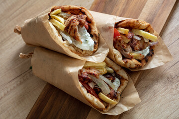 Gyro pita Shawarma wrap on wood table. Greek food with slice cut meat, overhead